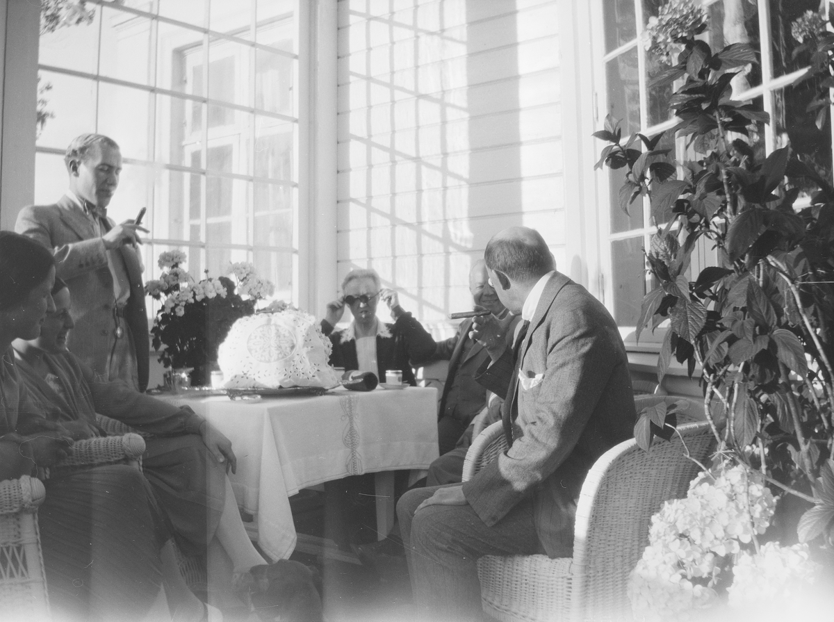 Fra venstre: uidentifisert kvinne, Iacob Ihlen Mathiesen, uidentifisert kvinne, uidentifisert kvinne, Christian Pierre Mathiesen, og en uidentifisert mann sitter på verandaen på Linderud Gård.