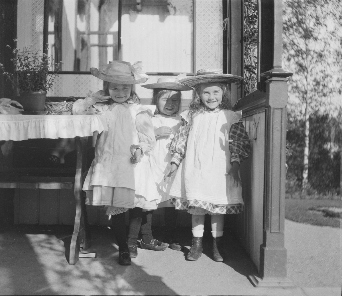 Tre smilende jenter på en veranda i sola, ytterst til høyre Ise (Louise) Mathiesen.