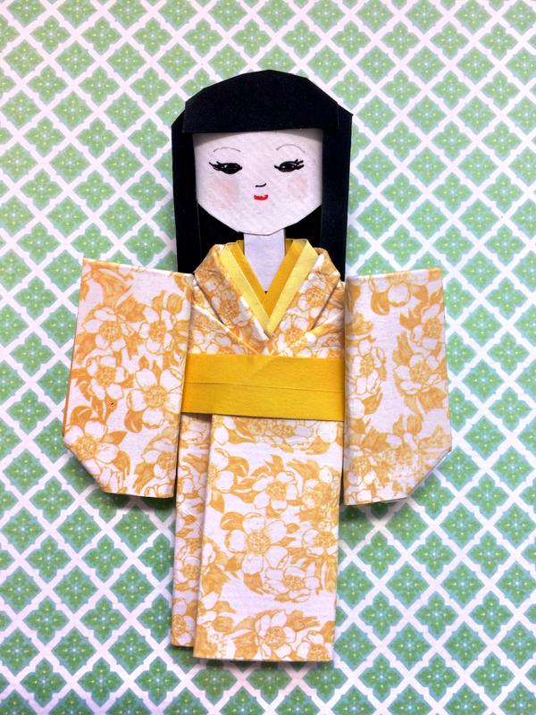 Papirdukke brettet i japanske origamiteknikk. Dukken har fått kimono i gult, blomstret papir. (Foto/Photo)