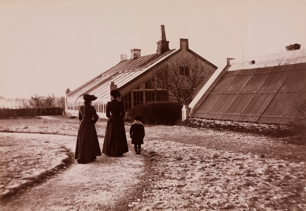 To kvinner og et barn foran veksthuset på Linderud Gård.