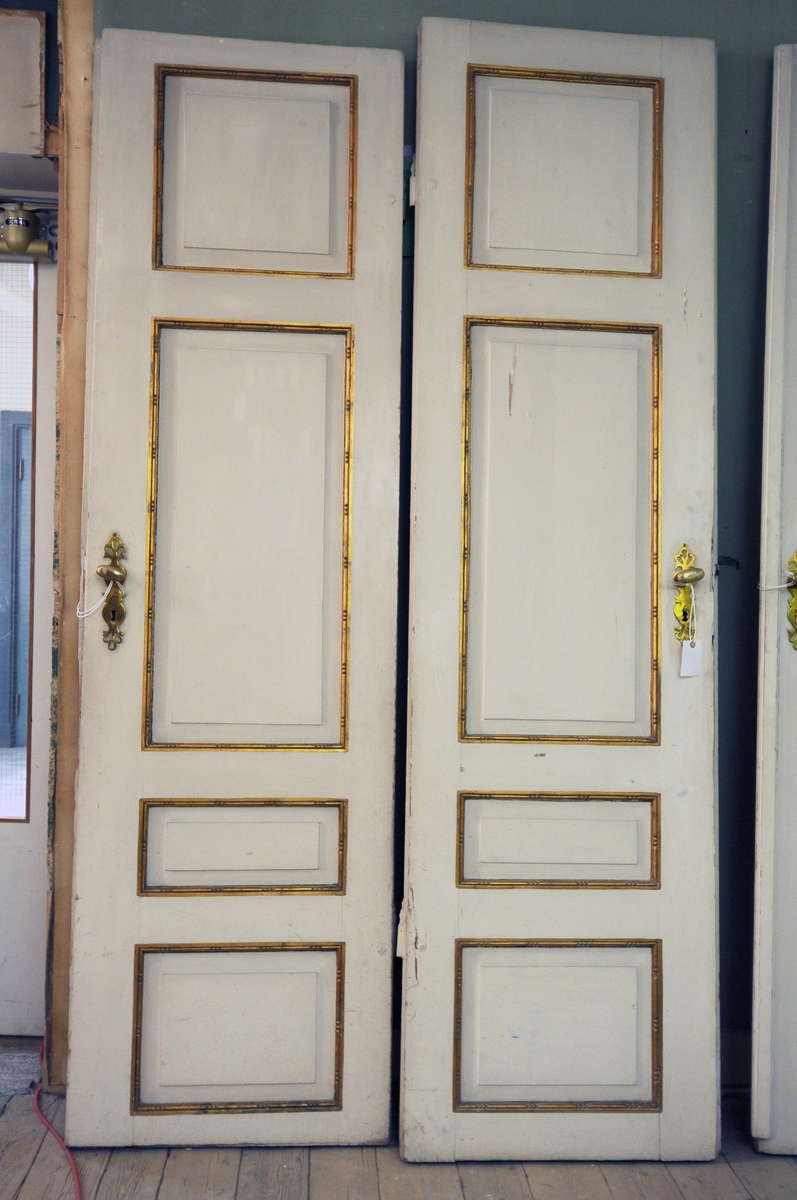 Dørkarm med terskel, to dørblad og gerikter. Dørene er hvite- og bronsemalte med skåret dekor rundt de fire fyllingene. Dørbeslag i messing. Hvite, profilerte gerikter med bronsemaling.