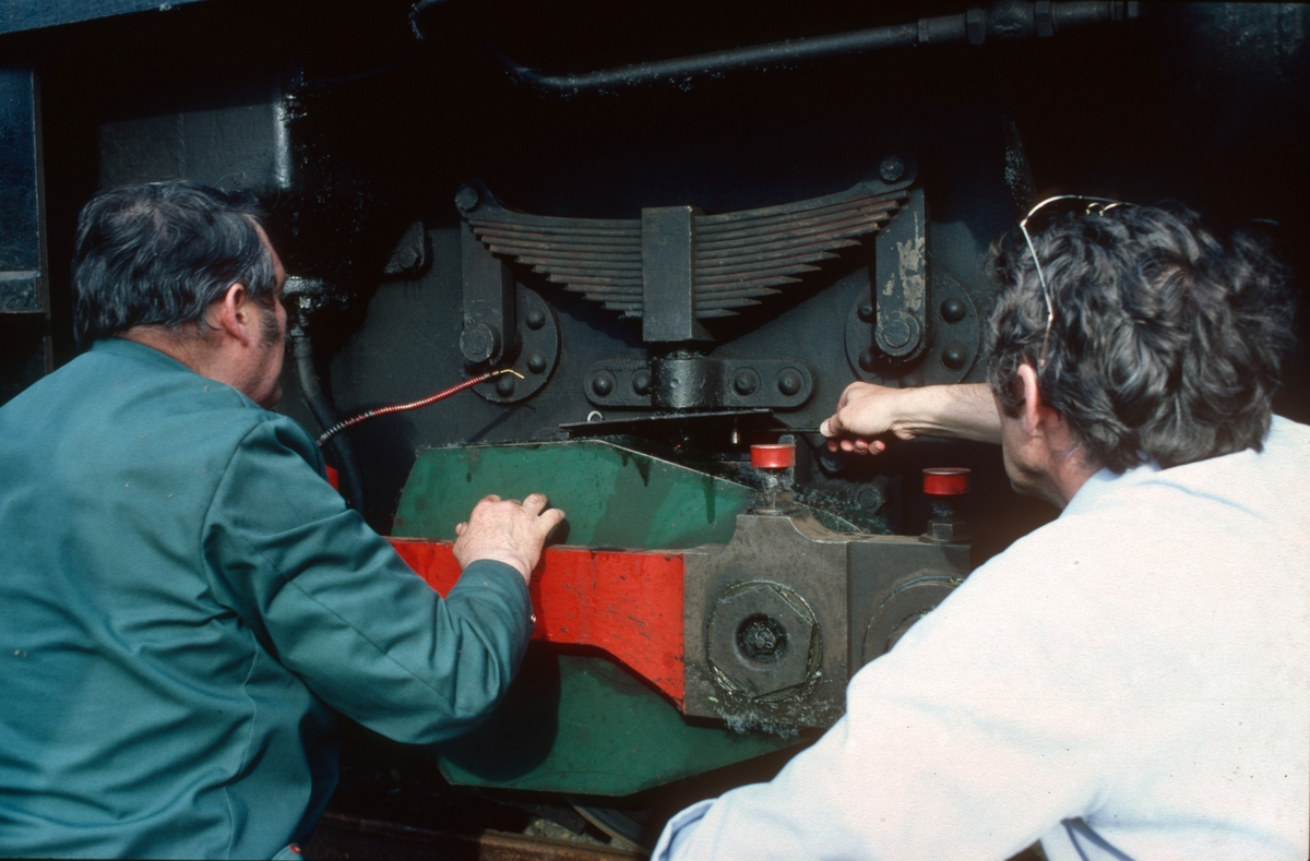 Lokomotivkontrollører i NSB, John Hjelde og Arvid Lie, instruerer personale på den nye museumsjernbanen. Her demonstreres smøring av akselkasse på diesellokomotiv nr. 10 (Ruston).