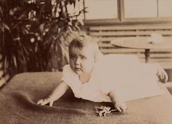 En baby (trolig Erica Mathiesen) ligger på et teppe på en gl