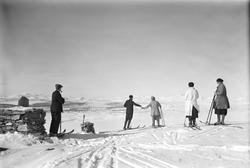 Øksendalskampen. Fem personer på ski. Tre damer med skjørt o