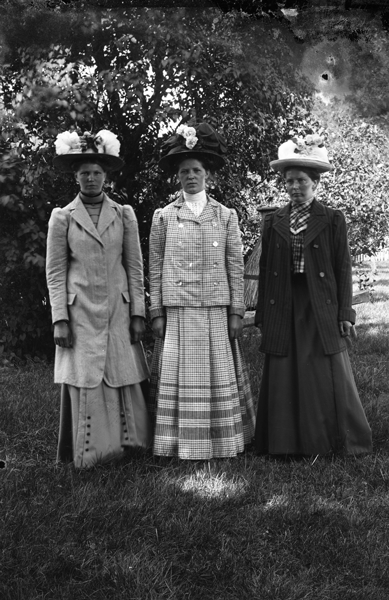 Gruppbild av tre kvinnor fotograferade utomhus.