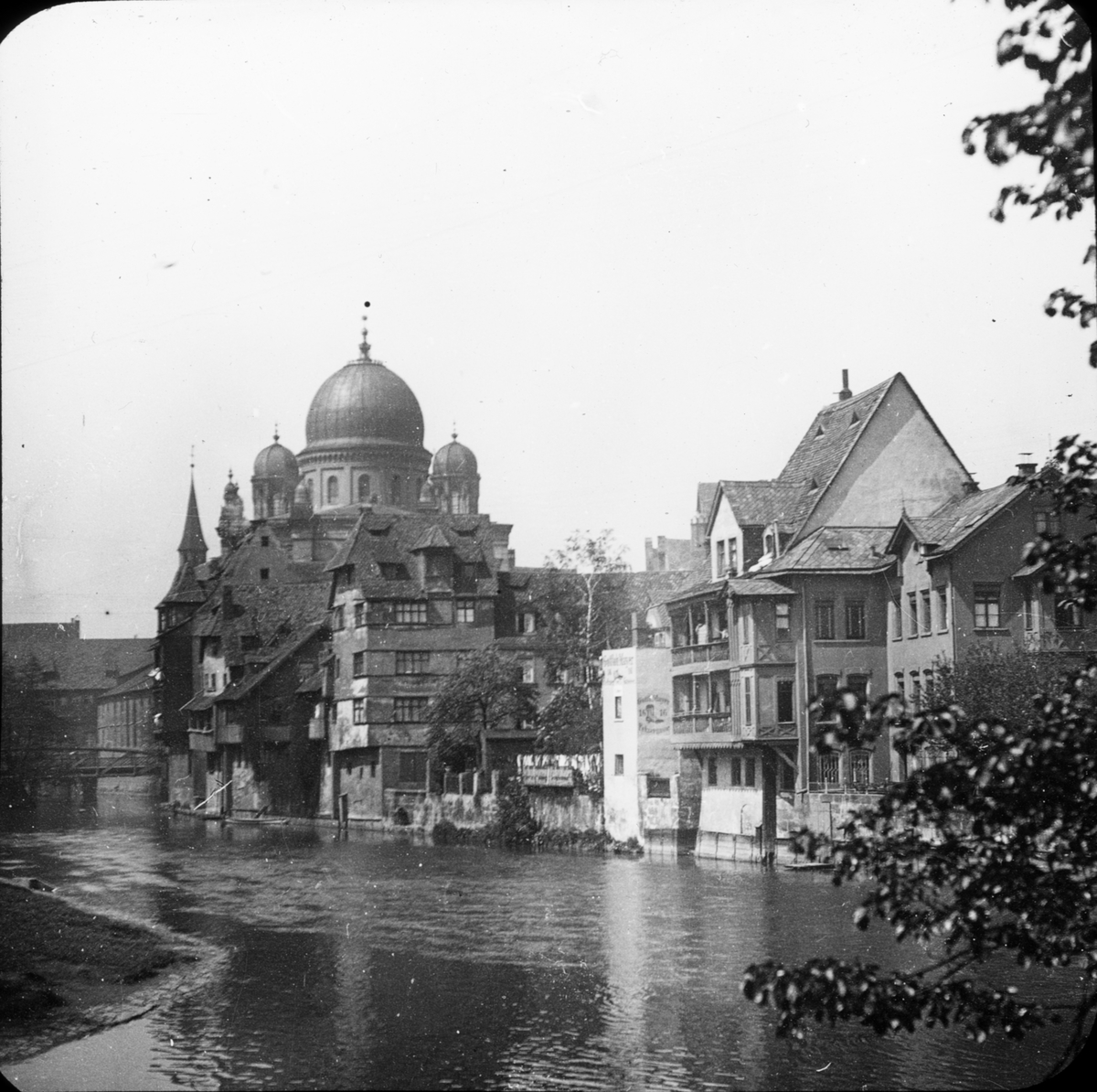 Skioptikonbild med motiv från Nürnberg, hus vid floden Pegnitz. Byggnaden med kupolerna är den stora Synagogan.
Bilden har förvarats i kartong märkt: Nürnberg. IV.