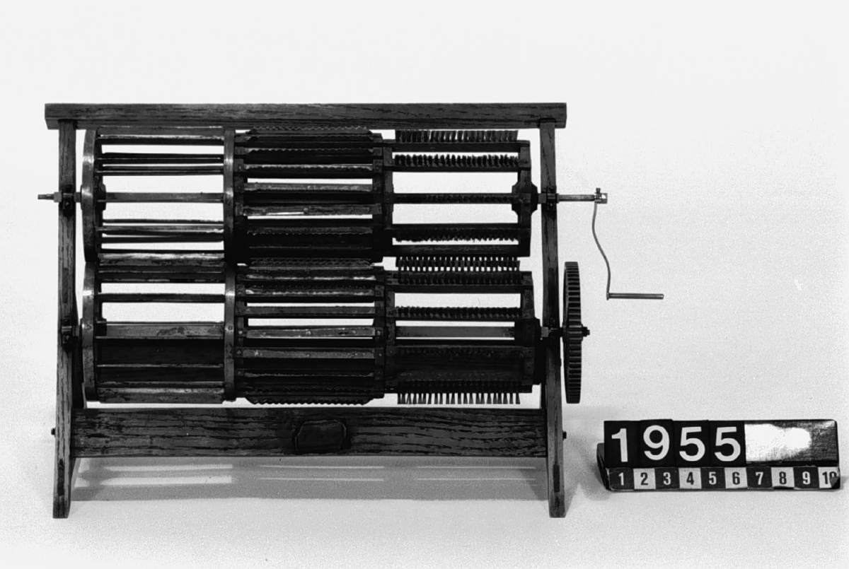 Modell av inrättning för bråkning, skäktning och borstning av lin, av Schwartz. Text på föremålet: "Maskin för bråkning, skäktning, häckling och borstning, av Svartz." på etikett,  och "Wallström 18 11/6 36" med bläck. N:o 89.