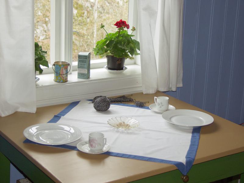 Kjøkkenbord dekket med hvit og blå duk og servise