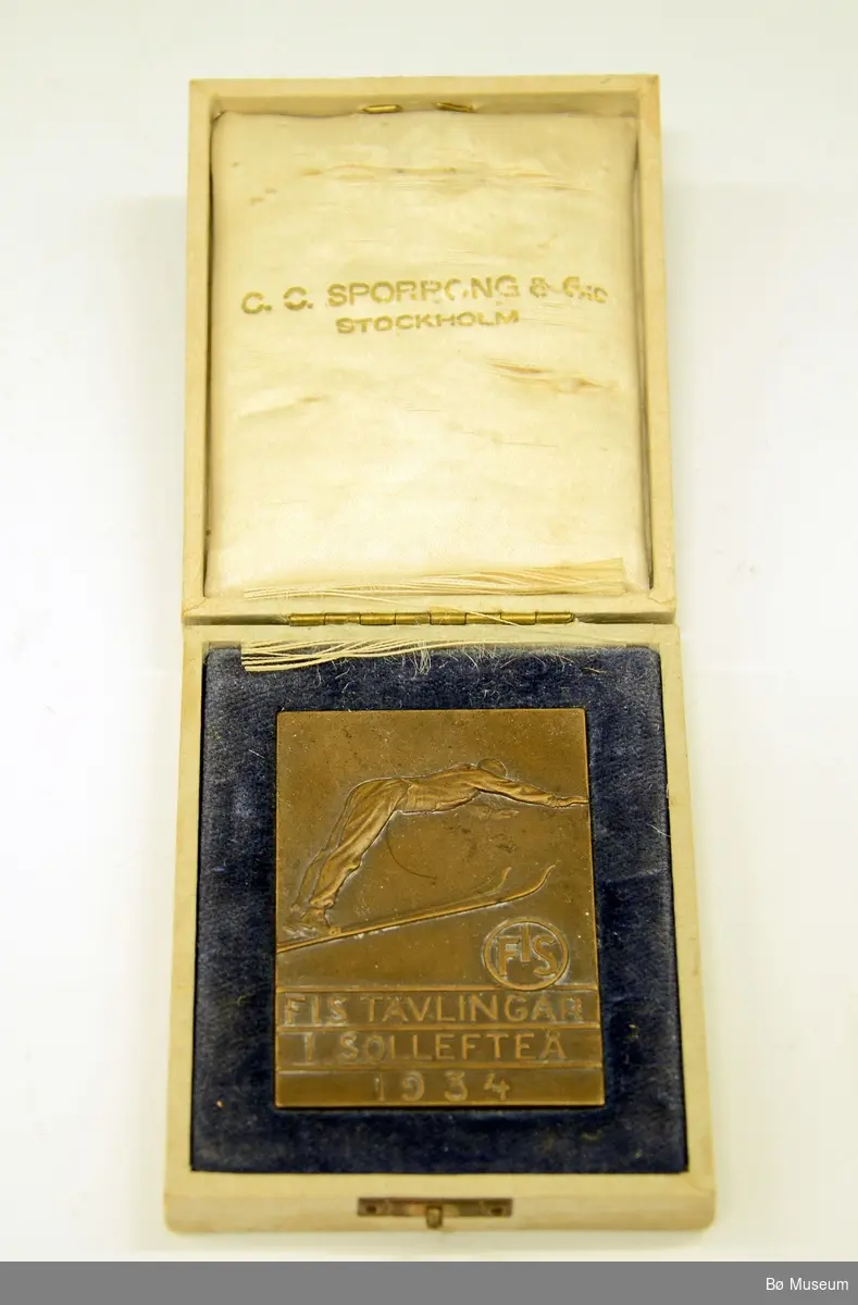 Deltakermedalje, "minnemynt". Fra Sollefteå, Sverige. FIS-hopprenn i 1934. Medaljen er laget av bronse, og ligger i etui.
Innskrift: FIS TÄVLINGAR I SOLLEFTEÅ 1934.