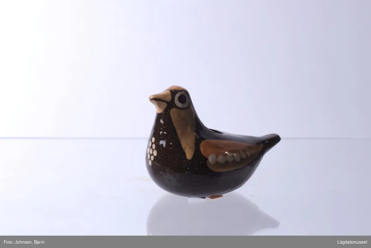 Det er ingen spesifikke motiv på gjenstanden, men utformelsen er en fugl. Motivene ellers består av ornamenter som danner blant annet vinger.