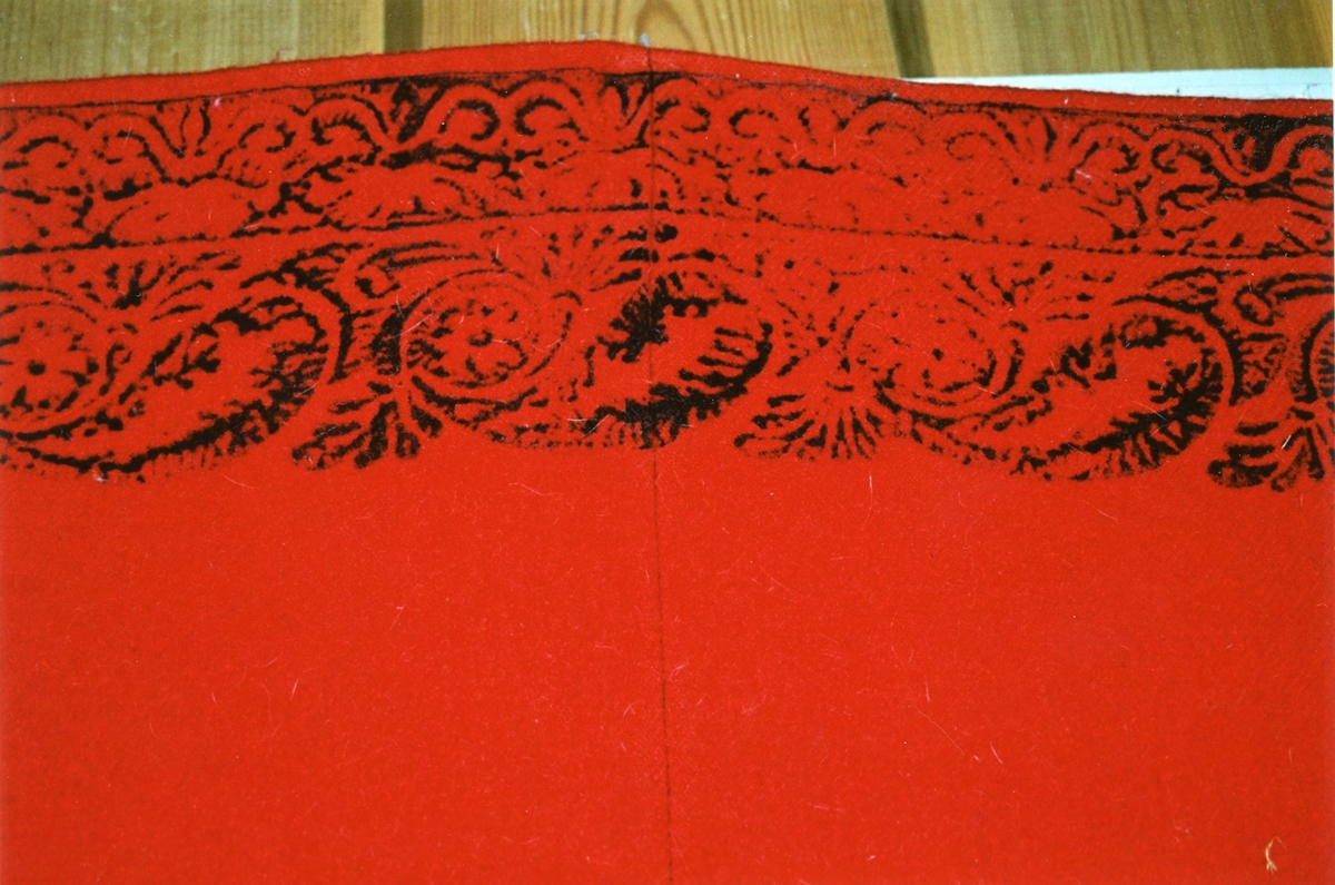 Fellåkle i lerret toskaft, med blokktrykket dekor. Åkleet er ved i sort og hvitt og seinere farget med rødt.
