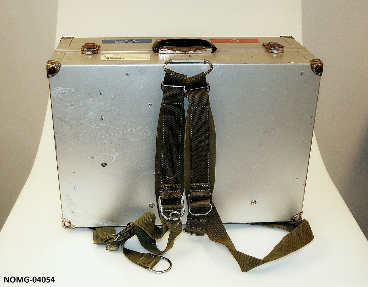 Legekoffert med hank og lås. Skulderrem på den ene siden. Tre rom inni med diverse medisinske utstyr.