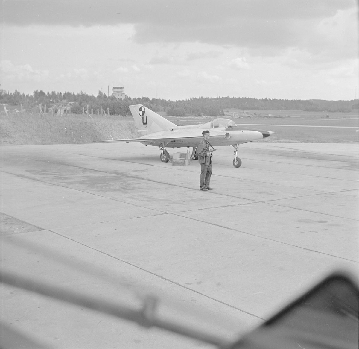Provflygplan Saab 210 Lilldraken bevakas av en beväpnad militär på flygfältet på F 8 Barkarby.