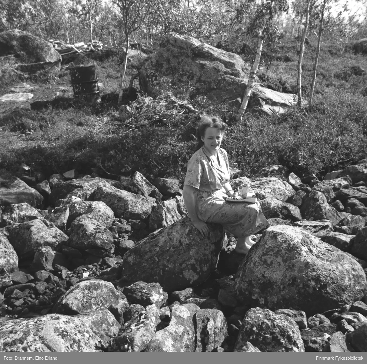 Olaug Gabrielsen sitter på en stor stein iført en kortermet sommerkjole.