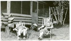 Burt Knatvold og kona som sitter utenfor hytta si ved Lake S