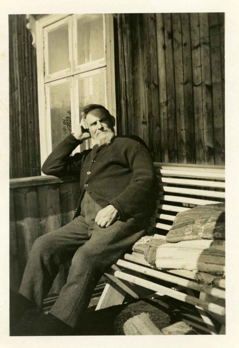 Hans Islandsmoen sitter på en benk foran hytta, sommeren 1932.