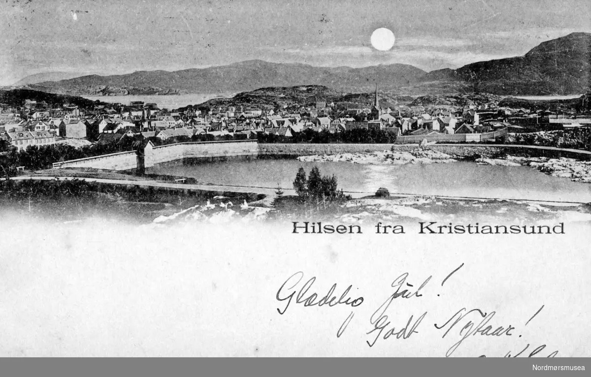 Postkort/julekort fra Kirkelandet i Kristiansund, hvor motivet er fra Vanndamman. Datering er trolig fra tiden omkring åpningen av vannmagasinet ca. 1914. Fra Nordmøre museums fotosamlinger.
