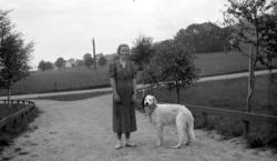 En kvinne på landeveien, ute på tur med hunden. Kvinnen er K