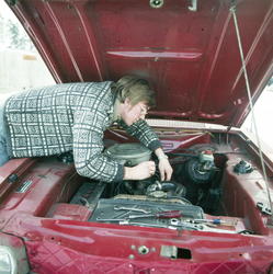 Mann arbeider i motor på bil