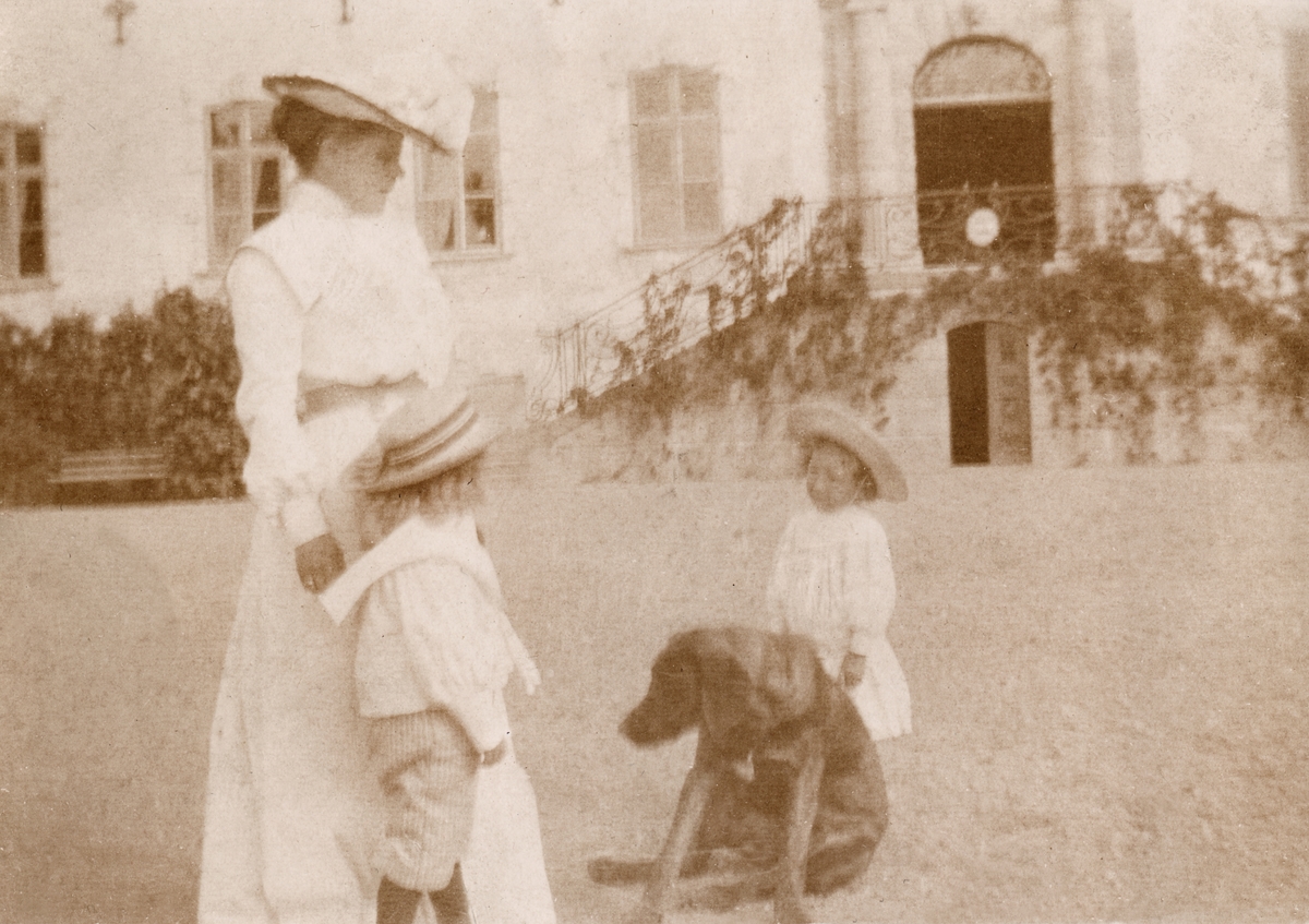Caroline Lagergren med sönerna Johan och Carl samt en hund på gårdsplanen vid Tyresö slott.