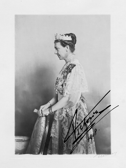 Porträtt av drottning Viktoria av Sverige. Hon står i profil, med händerna på en stol . Hon bär en finklänning och några halsband samt ett diadem.

Drottning Viktoria (1862-1930) g.m. Gustaf V. Diademet är det s.k. Leuchtenbergska diademet. (AB).