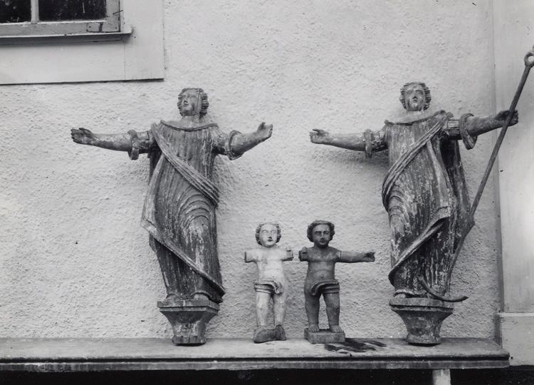 Foto på diverse träfigurer (antagl. från altaruppsats) utanför kyrkan.