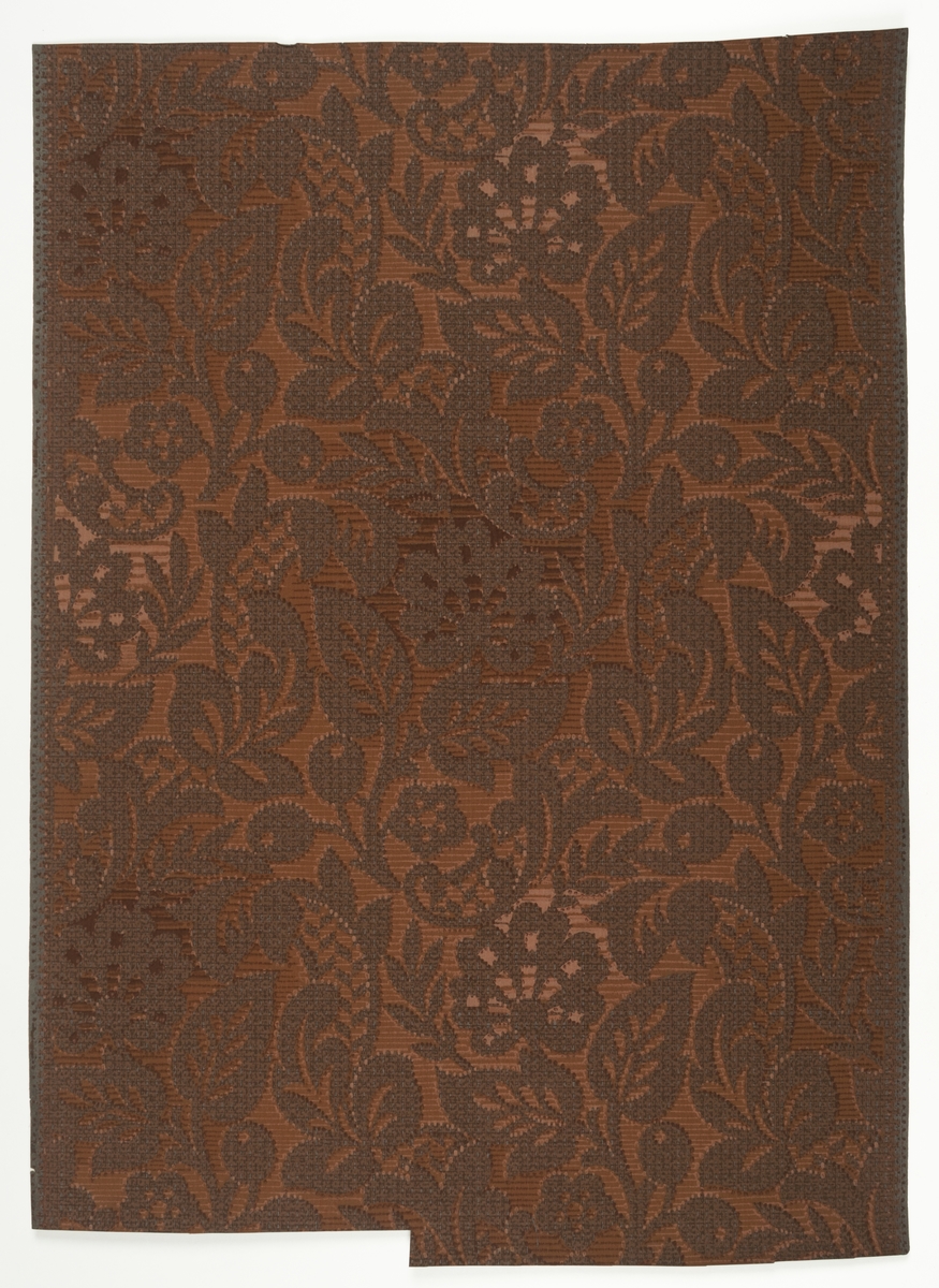 Textilimiterande blommönster av barocktyp i fyra bruna nyanser med schattering.  Obestruken botten, bottenfärgen utsparad i mönstret. Gråbrunt genomfärgat papper. IB
