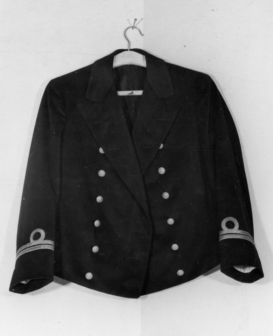 Mässdräkt för sjöofficer. Jacka av blått kläde försedd med gradbeteckning. 
Ovanför och intill översta galonen har tidigare funnits en ljusblå klädespasspoil, bottagen för reservofficerare 1926.