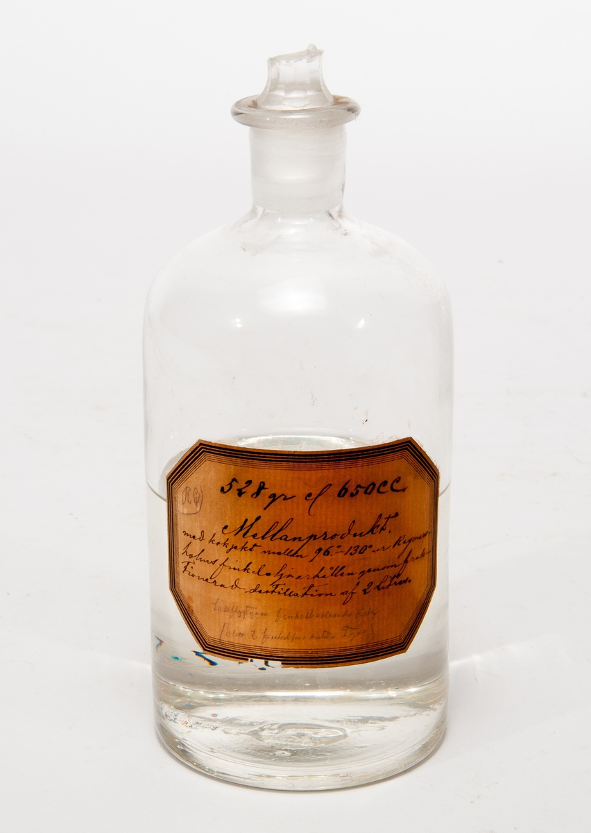 Finkelolja i  flaska av glas med etikett: "528 gr el 650 cc, Mellanprodukt, med kokpkt mellan 95-130 gr ur Rymersholms finkelolja erhållen genom fraktionerad destillation af 2 liter."
