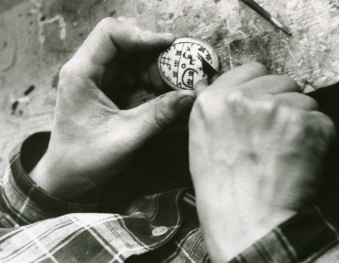 Närbild av konstnären Lars Piraks händer som arbetar med att karva in ett samiskt mönster i ett runt stycke, eventuellt av horn.