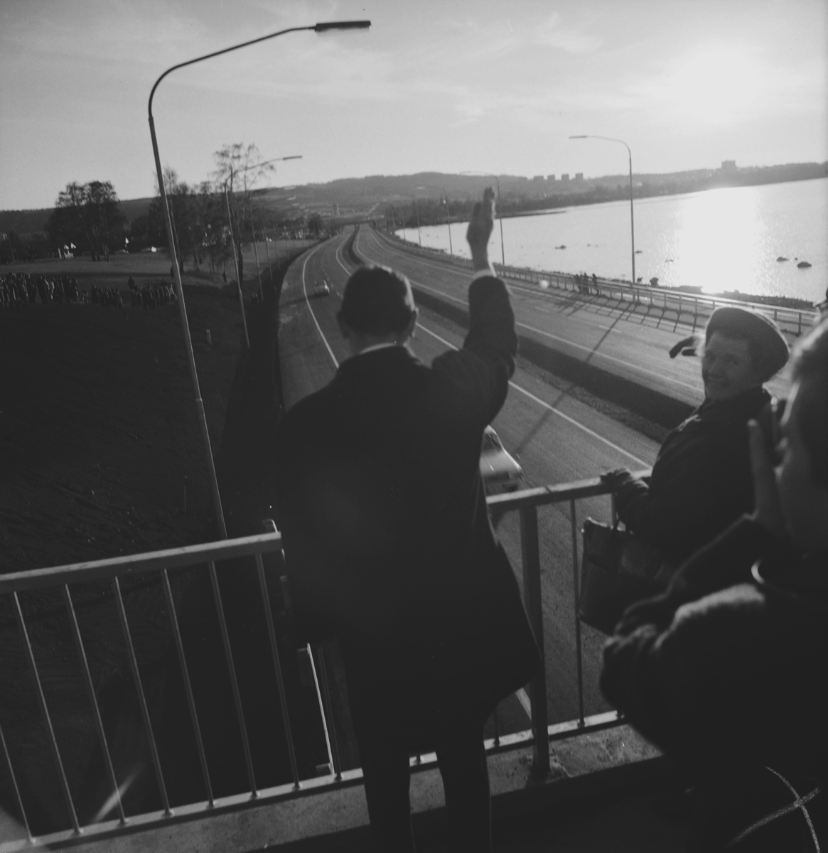 Landshövding Sven af Geijerstam står på bron vid Kruthuset i Huskvarna och vinkar åt trafiken som blivit påsläppt på den nya motorvägssträckan, E4, mellan Österängen och Brunstorp.