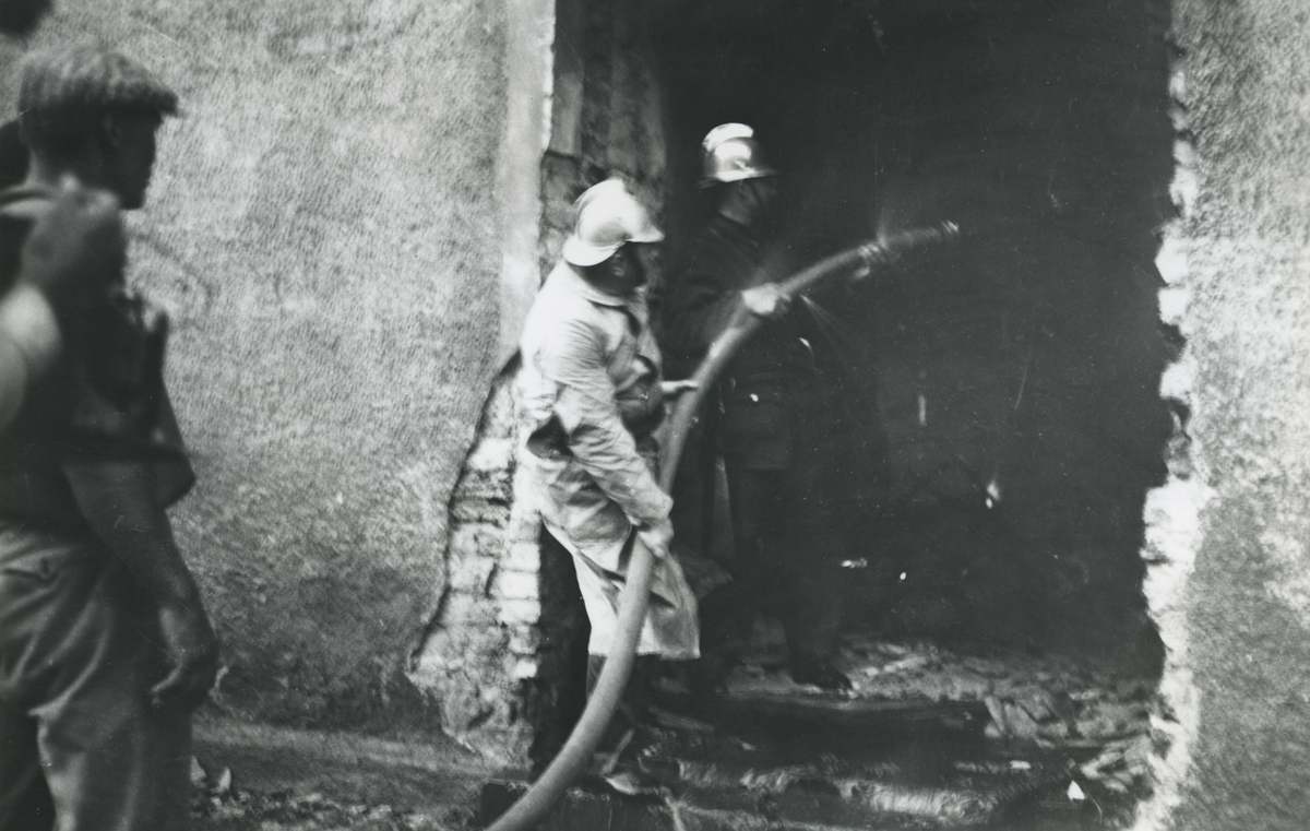 Ångkvarnen i Kalmar. Branden juli månad 1935. Brandmän sprutar vatten när folk kollar på.
