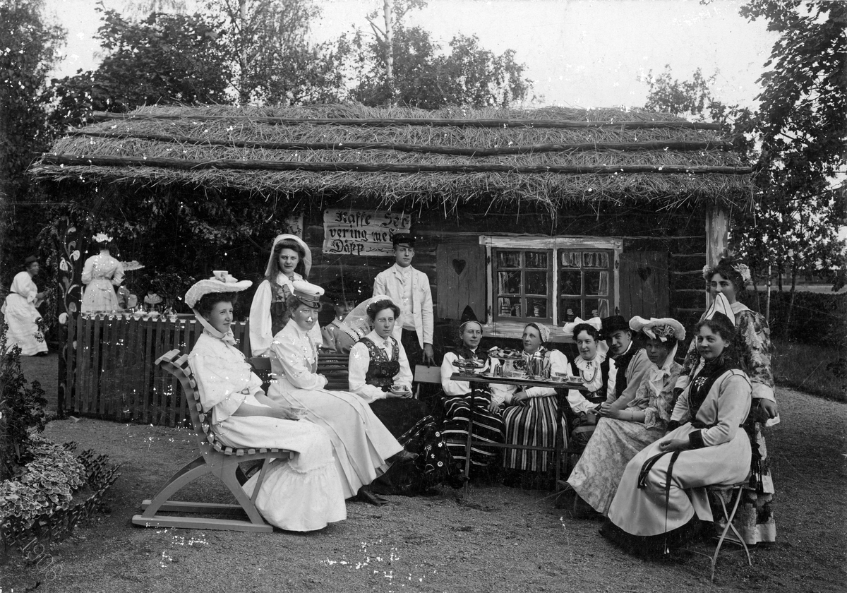 Kaffeservering på Alphyddan, 1906. Damer dricker kaffe. Litet hus med halmtak med skylten Kaffeservering med dåpp”.

Köpings spritbolags sommarschweizeri, Alphyddan.