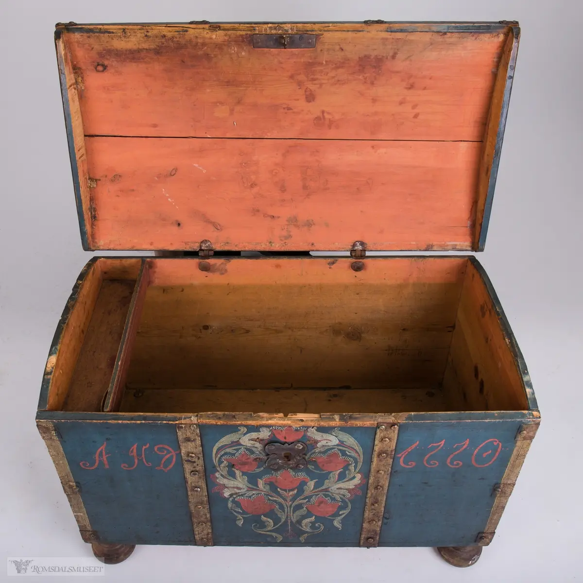 Rosemaling på blå bunn.  Det midtre feltet er dekorert med symetrisk rosemaling på blå bunn . I de to andre feltene på fronten er malt med initialene.