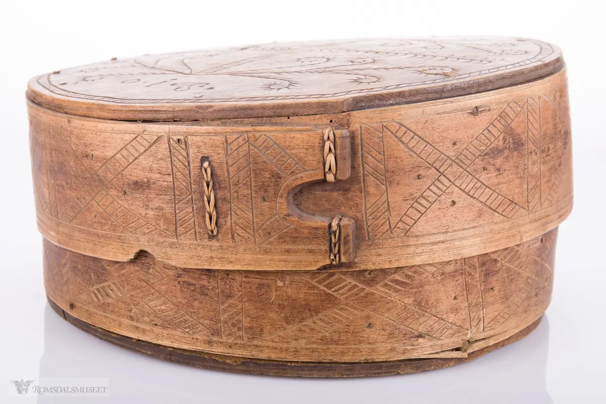 Eit kvistmønster/bregner på lokk. Skravert kryss- mønster langs trosken. Rosett av spetter i bunnen.