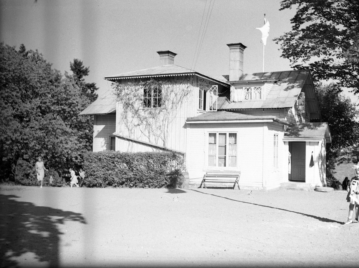 I.O.G.T:s sommarhem Lindesberg på Norrlandet, Gävle. Invigning den 30 juni 1940. Ägt av G.G.I.K. Godtemplarordens flagga är hissad. En mötesplats för ungdomar under krigsåren då Sverige var stängt. Det var fester, lekar, bad och dans på bryggan. Lindesberg låg vid viken mellan Frivy, Lervik och Kullsand. Revs när hamnen byggdes ut. Den som nu minns med glädje och tacksamhet dessa tider är nu 84-åriga Karin.