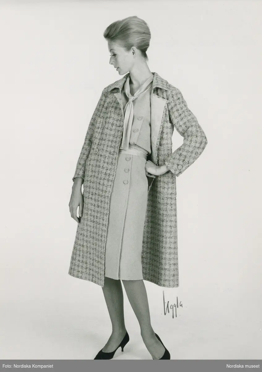 Modell i lavendelblå klänning och rutig kappa, håret i svinrygg och pumps med taxklack. Original från Chanel.
