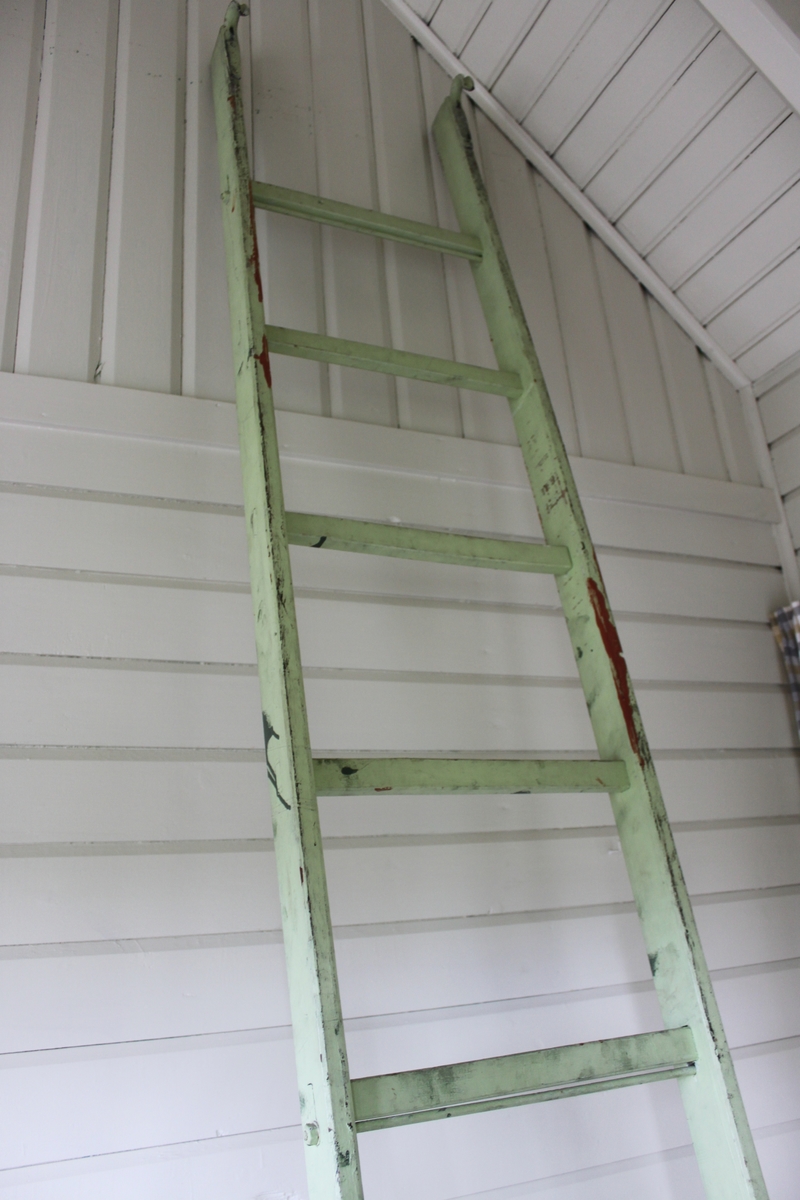 Trästege målad i ljusgrön färg. Vissa steg är stabiliserade med genomgående metallstänger. Högst upp är stegen försedd med två metallkrokar. Användes till vindsluckan i Kolonistugans förstuga.