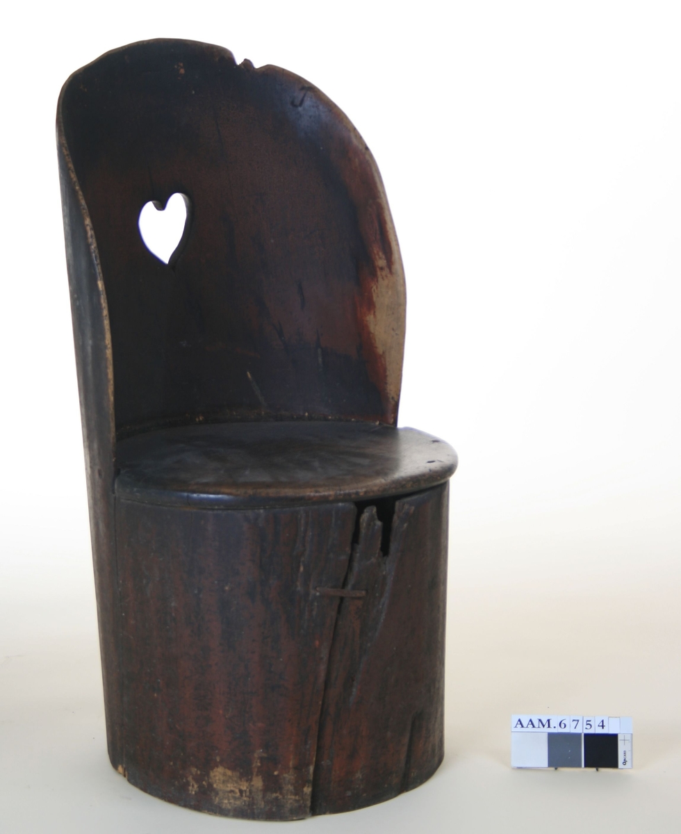 Kubbestol av forholdsvis spinkle materialer, hjerteformet utskjæring i ryggen, tilnærmet ovalt sete.