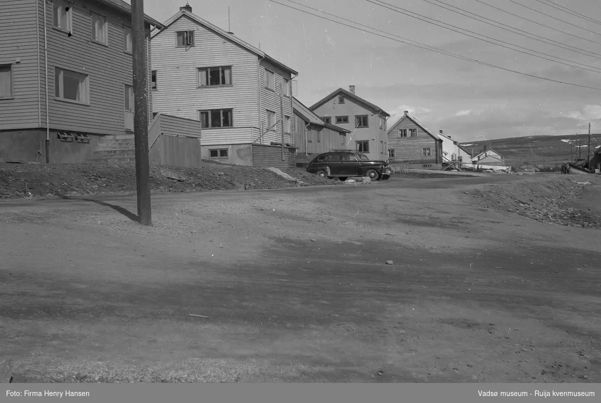 Oscarsgata i Vadsø sett fra vest mot øst.  Den hvite bygningen, nr to i bildet med en sort personbil parkert foran, er Niskagården. Gaten som går mellom bygning fire og fem er Kirkegata. Bygning nummer fem er muligens Bettenhuset. Bildet er tatt 17 mai 1951.