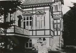 To kvinner i kjole står foran Berlihuset på Klokkerhaug i Sy