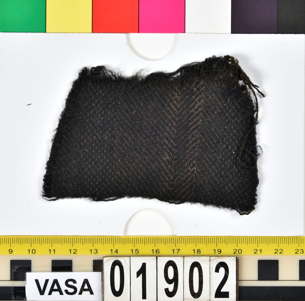 Textilstycke. Ett stycke väl bevarad vävd textil. Vävd med brun och svart ylletråd.