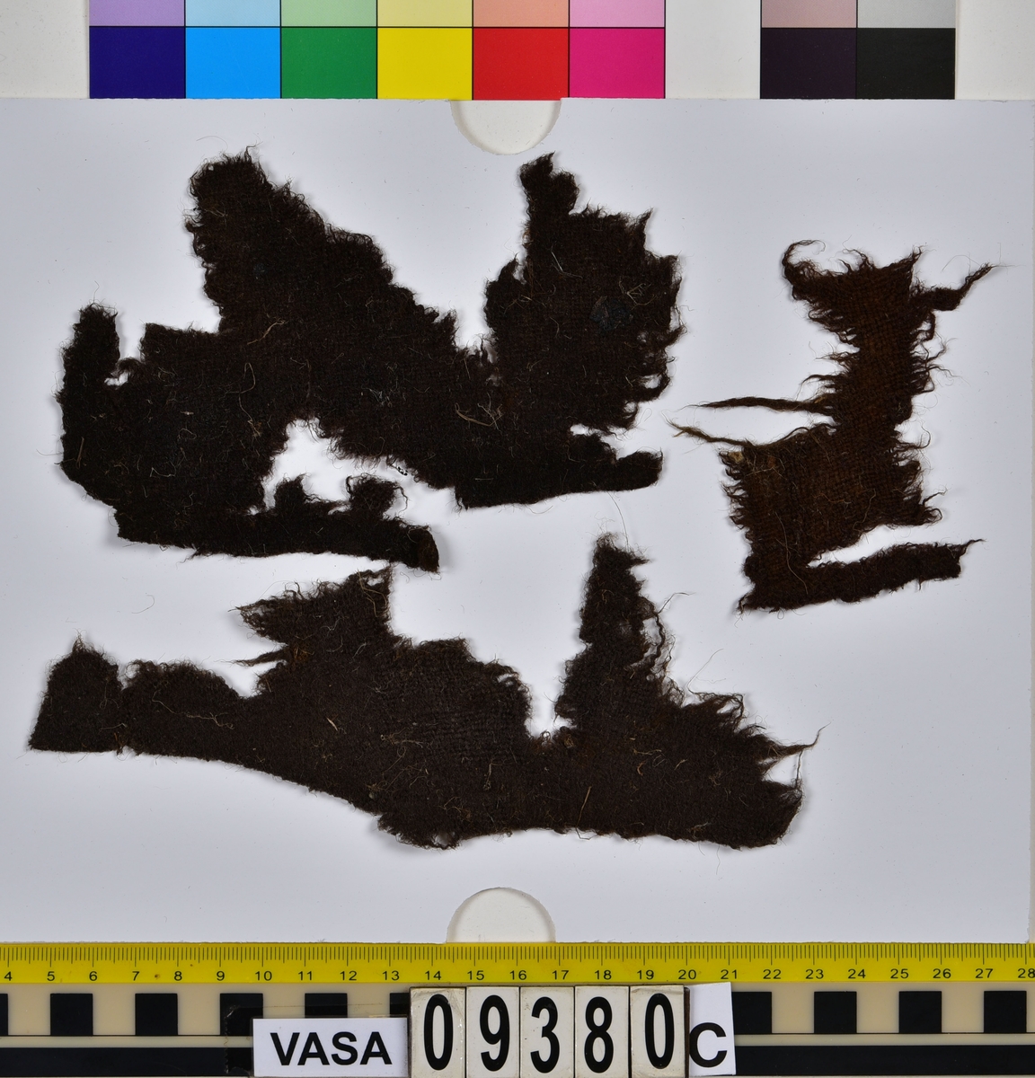 Fyndnumret innehåller fyrtio stycken textilfragment som kommer från sju olika textilier. Tre av dem är tyger av ull vävda i tuskaft, två är tråd varav den ena är av silke och den andra av ull och två är filtade fragment av ull. Flera av fragmenten är troligen dräktdelar. Trådarna är sydda till några av de filtade fragmenten.
.
Textildokumentation 2019.
Textil, fyndnumret består av 40 st fragment uppdelade på 09380a-c.
Kontextgrupp ÖB25 (övriga fyndnummer i gruppen: 03395, 09387 och 27905).
Relaterade fynd i andra kontextgrupper: inga
.
Fnr 09380a Typnr ÖB25.4:1-31.
Sammanfattning -  31 stycken textilfragment av ull, filtade. Färgen är nu mörkt brun, originalfärg okänd. Fibrerna är relativt grova, raka och väl synliga, det vill säga att filten är olik den fina hattfilt som finns i flera fyndnummer i samlingen. En kant på ett av de större fragmenten kan möjligen vara tillskuren. I övrigt finns inga originalkanter eller andra spår av sömmar, tillskärning eller liknande. På båda sidors yta finns en del spridda växtfibrer.
.
Fnr 09380b Typnr ÖB25.5:1-2.
Sammanfattning - Två textilfragment av ull, filtade. Färgen är brun i en gröntonad nyans, originalfärg okänd. Filten är styv, fibrerna är fina. Likadan filt finns i 09387 ÖB25.5:3-4. 
Fragment ÖB25.5:1 - Det större fragmentet. Fragmentet har en tillskuren kant, inga sömmar finns. Ytan på sida A är bättre bevarad än sida B och har en homogen färg. Ytan på sida B är ojämn, där ytan är bortnött är filten mer gröntonad. På båda ytorna finns mindre rester av växtfiber.
Fragment ÖB25.5:2 - Fragmentet har inga tillskurna kanter. I fragmentet sitter fast flera trådar, se 09380b ÖB25.6:1-2 samt 09380b ÖB10:1-2. 
.
Fnr 09380b Typnr ÖB25.6:1-2.
Sammanfattning - Två trådar av silke. Trådarna sitter fast i fragment 09380b ÖB25.5:2 (filt). I samma fragment sitter även trådarna 09380b ÖB25.10:1-2. Likadan tråd finns i 09387 ÖB25.6:3.
Fragment (tråd) ÖB25.6:1 - Cirka 200 mm lång. Är sydd igenom det filtade fragmentet 09380b ÖB25.5:2 på två ställen. Mellan genomförningarna ligger den över tråden 09380b ÖB25.10:1. Tråden är 2-trådig och s-tvinnad. Tråden har en knut (eller dylikt).
Fragment (tråd) ÖB25.6:2 - Cirka 50 mm lång. Sitter fast på en del av tråd 09380b ÖB25.10:2. Tråden är både knuten och tvinnad till denna. På båda trådarna finns rester av någon substans. Tråden är 2-trådig och s-tvinnad. 
.
Fnr 09380b Typnr ÖB25.10:1-2.
Sammanfattning - Två trådar av ull. Trådarna sitter fast i 09380b ÖB25.5:2 (filt). I samma fragment sitter även trådarna 09380b ÖB25.6:1-2 fast. Eventuellt är tråden 09387 ÖB25.11:1-5 av samma typ trots att den tråden är 4-trådig. Det är möjligt att två av trådarna som tvinnats till tråden ÖB25.10 brutits ned och nu är hel försvunna, tendenser att detta har hänt i partier även på 09387 ÖB25.11:1-5 finns.
Fragment (tråd) ÖB25.10:1 - Cirka 110 mm lång. Är i ena änden hoptvinnad med ÖB25.10:2. Är på större delen av sin längd hoptvinnad, hopknuten och hoplimmad(?) med tråden 09380b ÖB25.6:2. Måtten är ungefärliga då mätning varit svår pga att tråden sitter ihop med andra trådar.
Fragment (tråd) ÖB25.10:2 - Cirka 85 mm lång. Är i ena änden hoptvinnad med ÖB25.10:1. Sitter fast under tråden 09380b ÖB25.6:1.
.
Fnr 09380c Typnr ÖB25.7:1.
Sammanfattning - Ett textilfragment av ull vävt i tuskaft. Färgen är nu brun, originalfärg okänd. Textilien är något ruggad på sida A. På sida B finns ingen lugg. Väven är tät och jämn. Garnet är jämt spunnet. Fragmentet har en tillskuren kant som har ett brott mitt i. Enstaka hål finns längs kanten, troligen efter en söm. På sida A finns rester av växtfibrer, enstaka rester finns även på sida B. Typen liknar 09380c ÖB25.8:1.
.
Fnr 09380c Typnr ÖB25.8:1.
Sammanfattning - Ett textilfragment av ull vävt i tuskaft. Färgen är nu brun, originalfärg okänd. Tyget har bitvis en ruggad yta på båda sidor. Väven är tät och jämn men trådsystemen ligger inte i rät vinkel på hela fragmentet (tyget har troligen brustit och dragits isär). Fragmentet har tre tillskurna kanter, hål efter sömmar kan anas. På båda sidor finns rester av växtfibrer. Typen liknar 09380c ÖB25.7:1.
.
Fnr 09380c Typnr ÖB25.9:1.
Sammanfattning - Ett textilfragment av ull vävt i tuskaft. Färgen är nu brun (rostbrun) originalfärg okänd. Garnet är mycket slätt och blankt, inga spår av ruggad yta finns. En av fragmentets kanter kan eventuellt vara en rest av en tillskuren kant eller en kant som brustit i sömmen. På båda sidornas yta finns rester av växtfibrer.