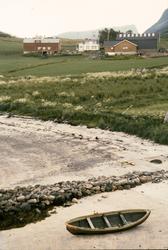 Bebyggelse på Elgsnes. I forgrunnen en robåt i fjæra.