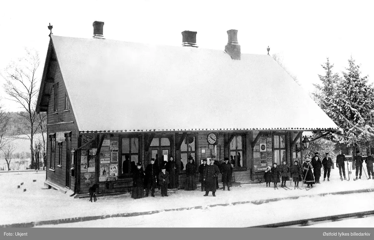 Råde jernbanestasjon med reisende passasjerer i vinterdrakt.