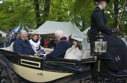 Kongeparet vinker til folket mens de kjører åpen hestevogn gjennom markedet på Hamar Middelalderfestival.