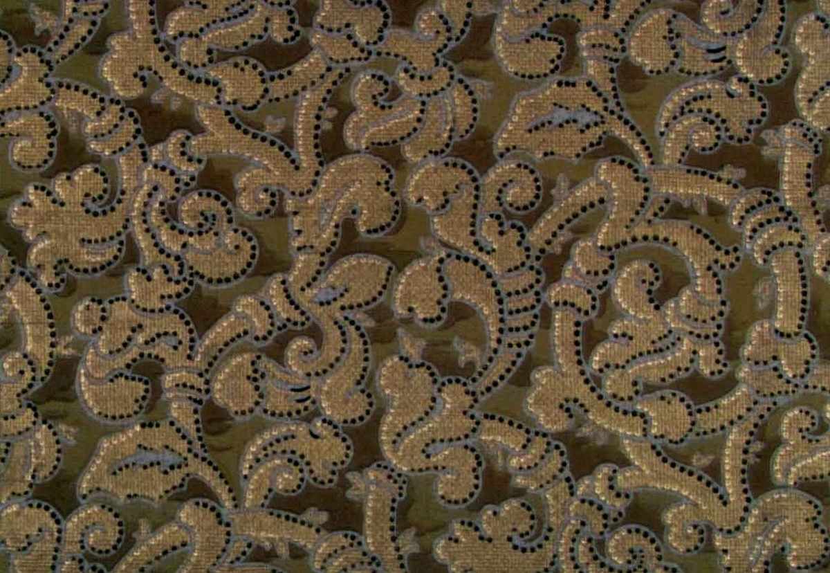 Ett tätt yutfyllande slingrande rep-mönster dekorerat med prickar i koppar, guld och svart samt i två bruna nyanser på en ljusgrå bakgrund.