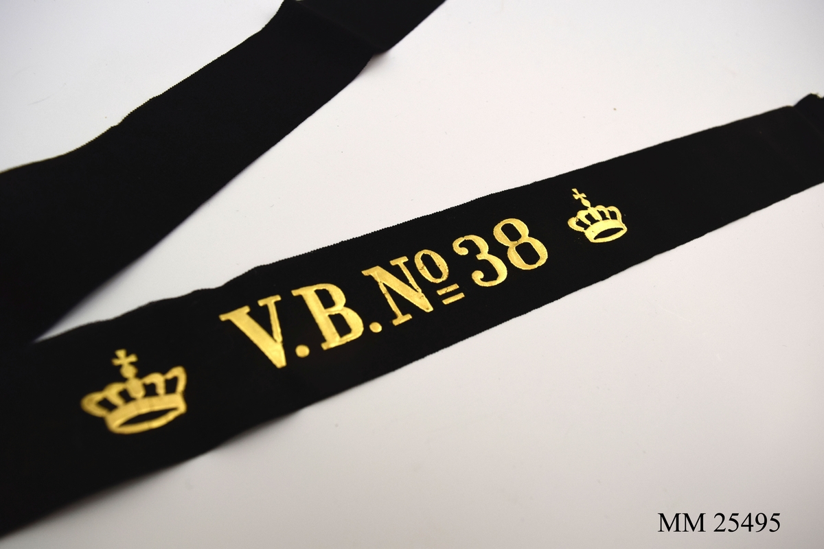 Mössband av svart sidenrips. Guldfärgad text, "V.B. NO 38", med två kronor på vardera sida.