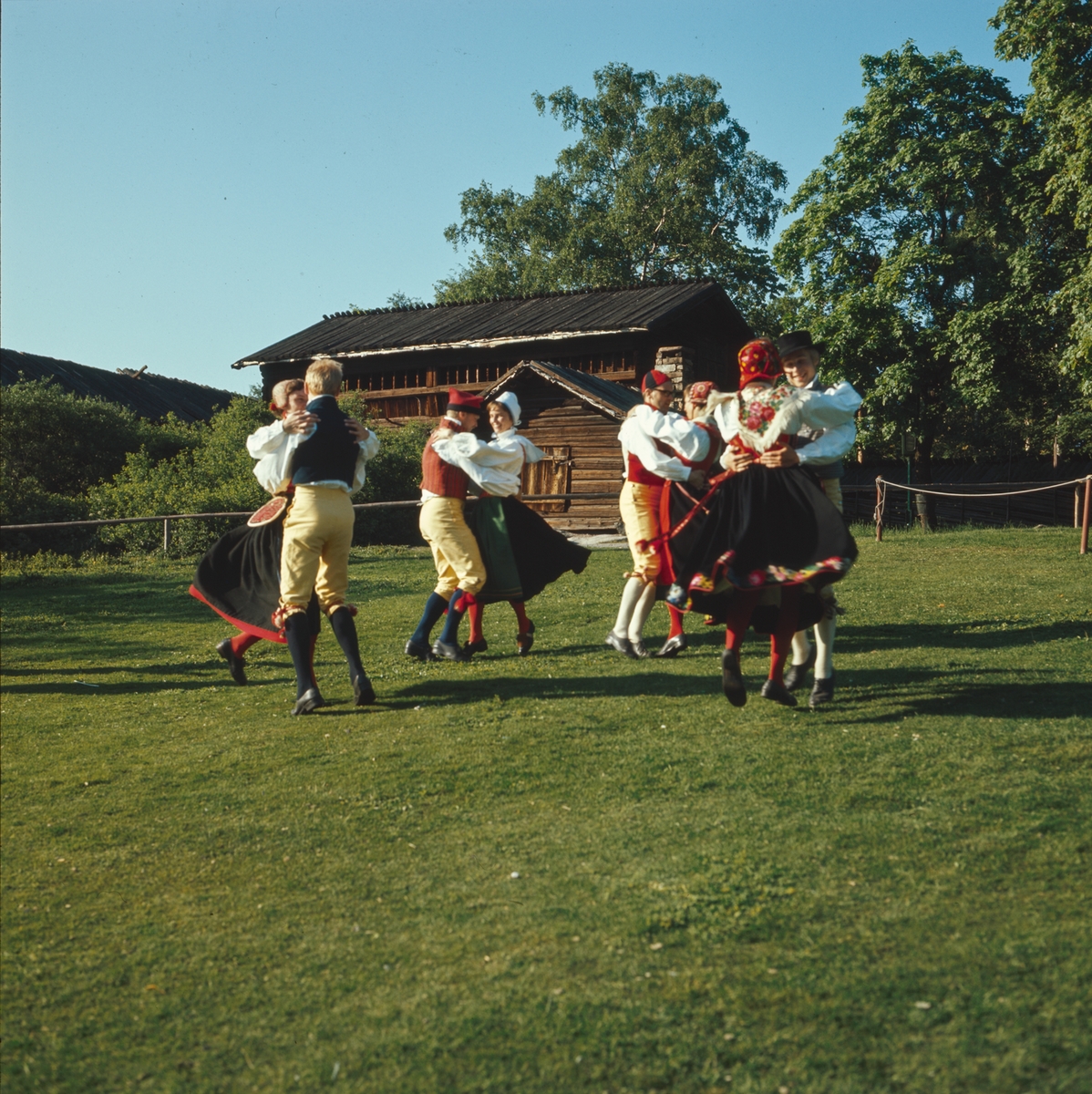 Ett folkdanslag dansar på Orsakullens gräsplan.