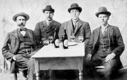 Gruppeportrett med fire trøkstinger rundt et bord i fotograf